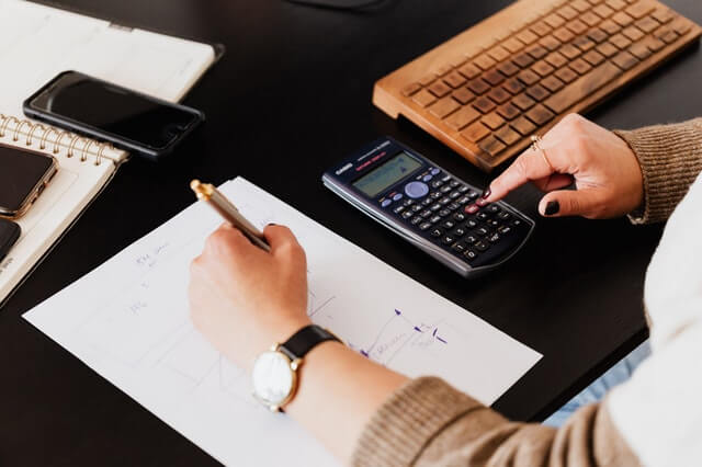 Servicios Crop Woman Using Calculator And Taking Notes On Paper